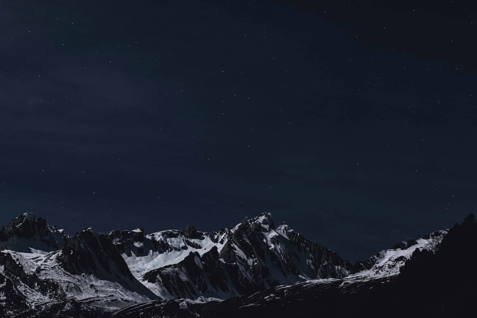 A mountain range at night with a starry sky.